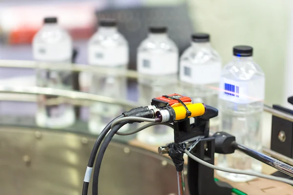 Machine vision inspection camera observing bottles on a production line